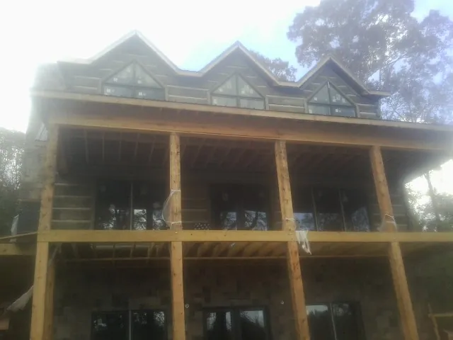 Dormers and porch framing on a large log home under construction — Roof Coating work by our crew in Jamison