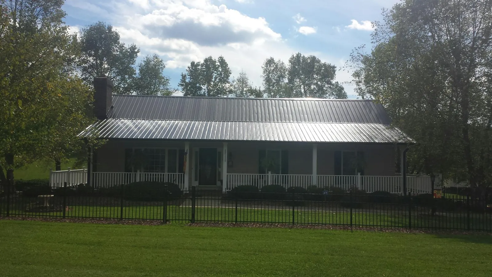 Gray metal roof on a brick ranch with a full width front porch — Gutter Guard Installation work by our crew in Jamison
