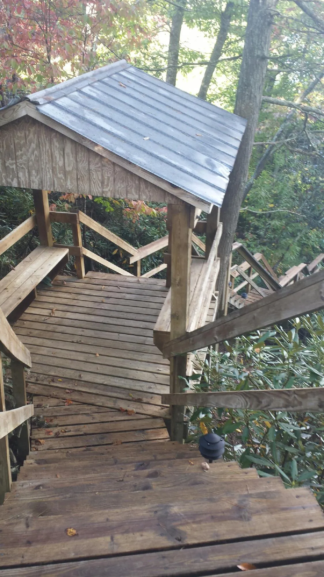 Metal roofed shelter over wooden steps on a wooded walkway — Skylight Repair & Installation work by our crew in Jamison