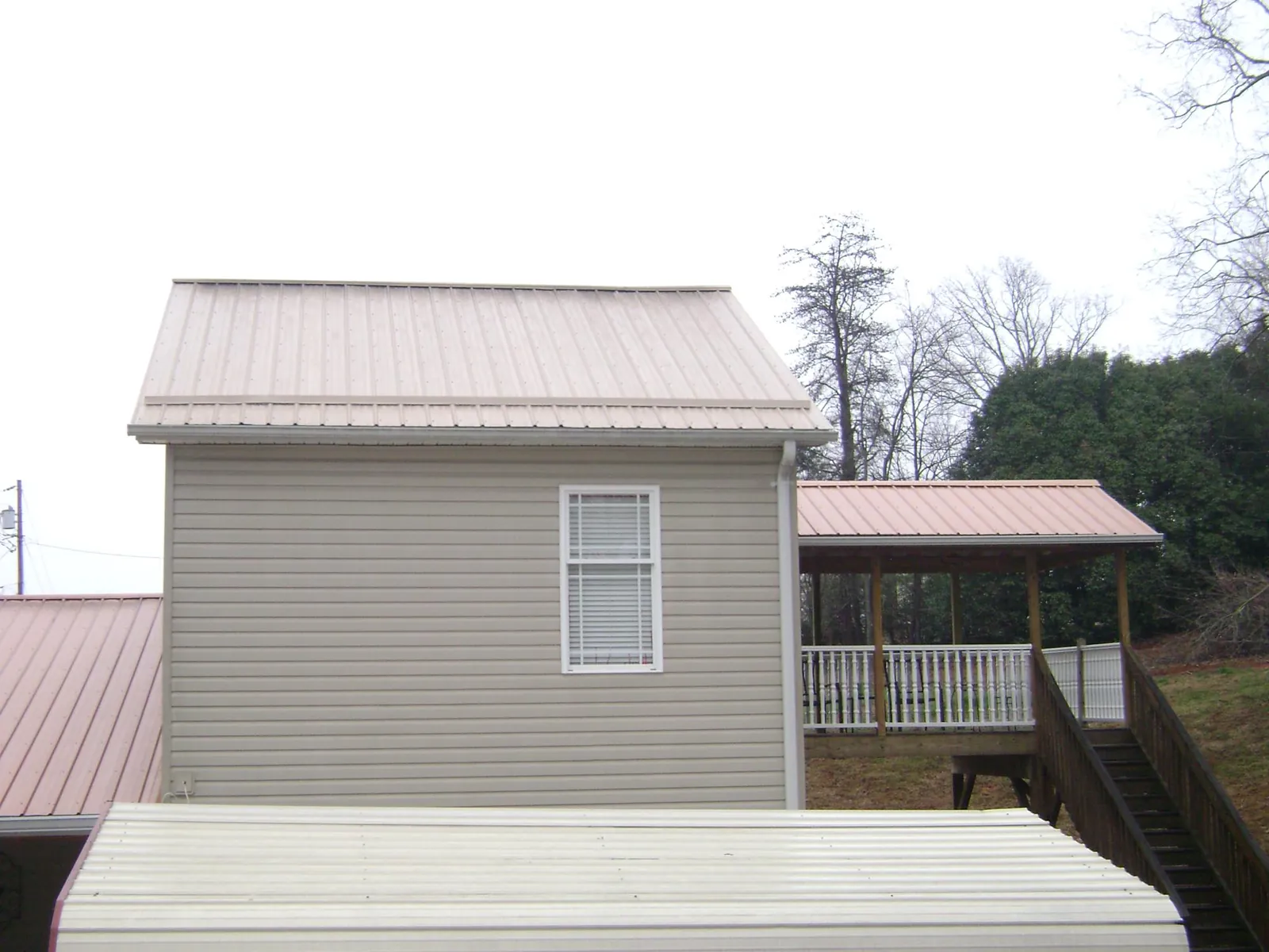 Tan metal roofs on a two story addition and attached porch, from a Roof Replacement job in Jamison