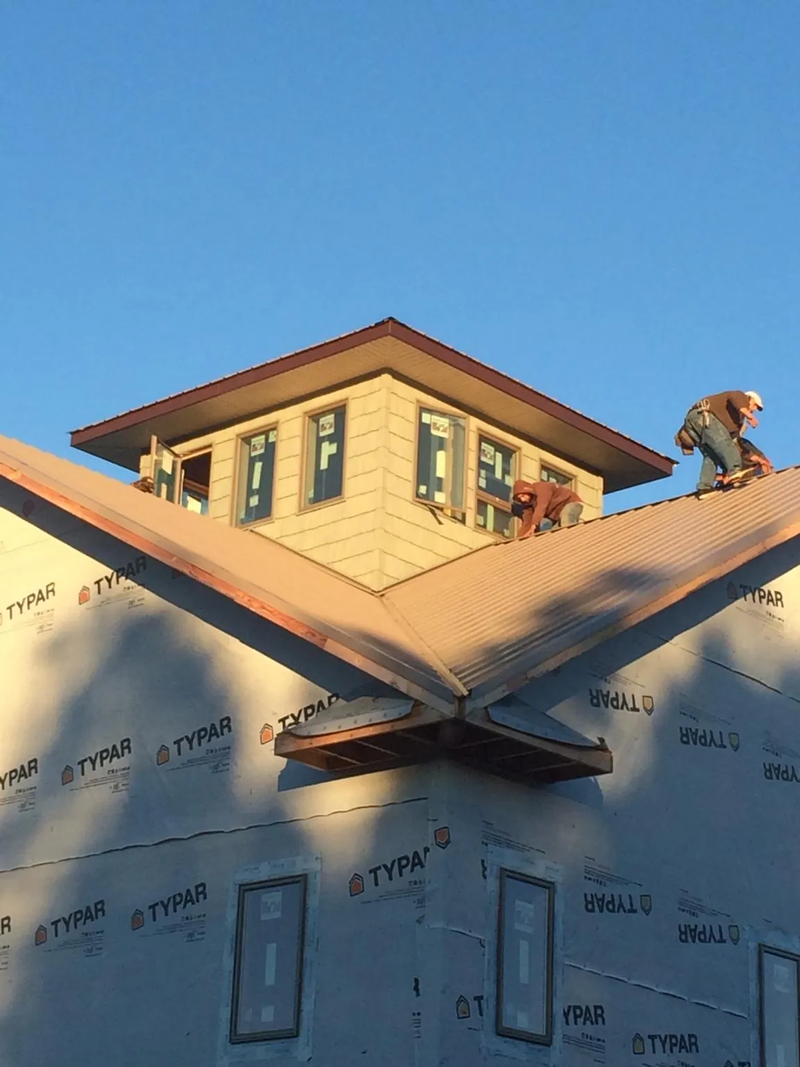 Roofers working around a rooftop cupola on a new metal roof at sunset — Roof Waterproofing in Jamison by Roofing Brothers